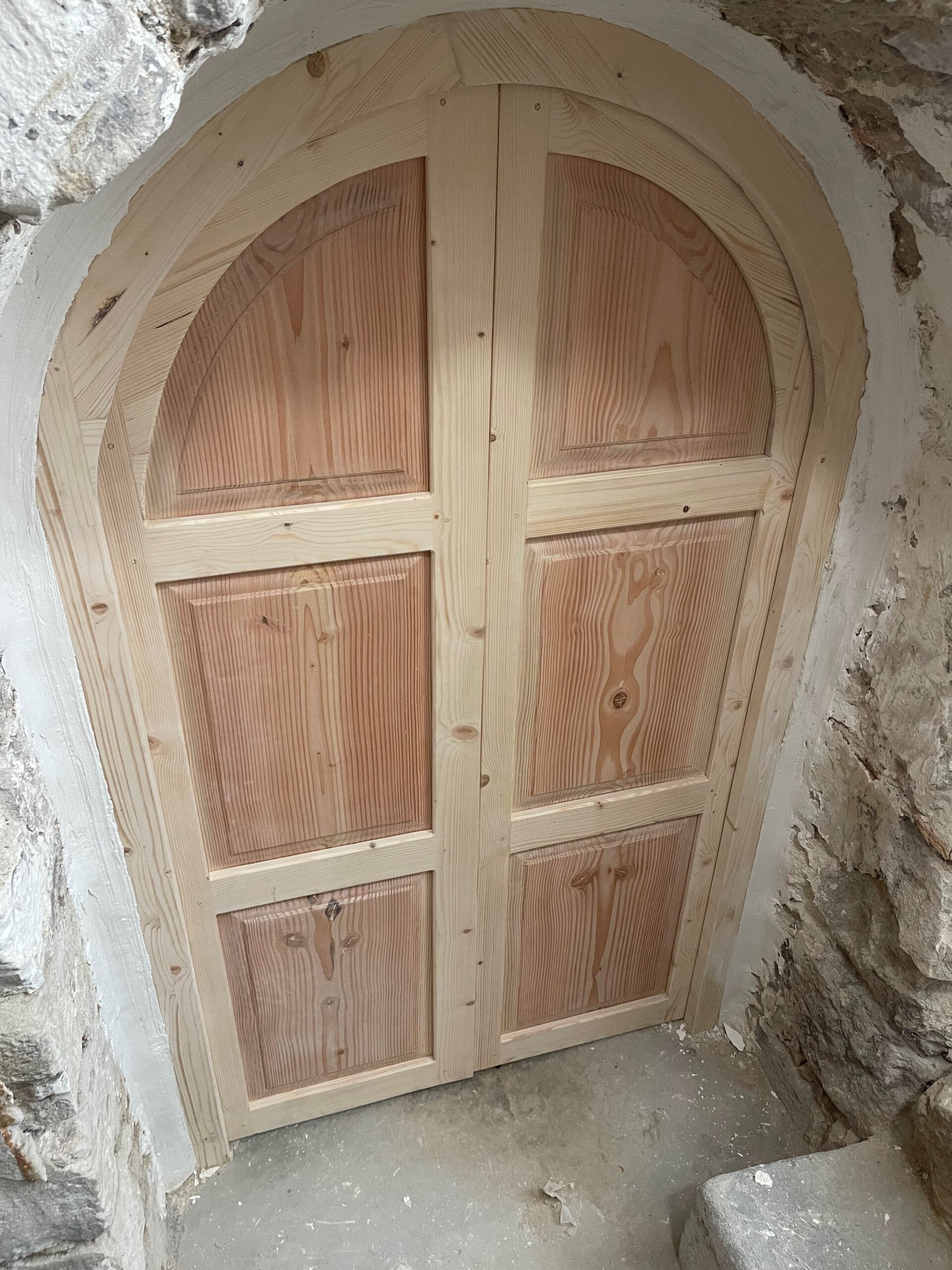 IMG_1722 Une porte en bois encadrée par un arc en pierre, symbolisant l'élégance et la durabilité des constructions anciennes.