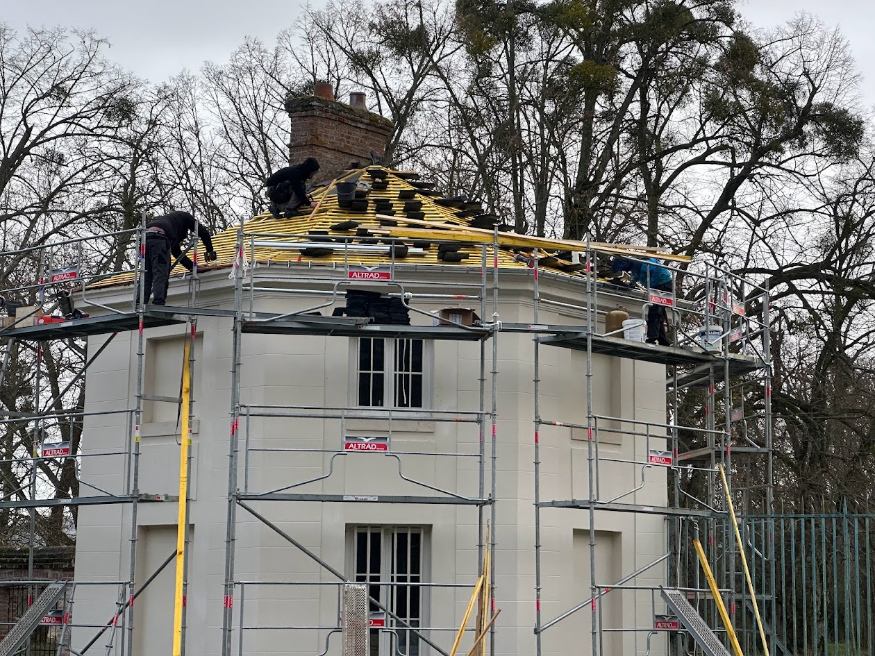 Un homme effectue des travaux sur le toit d'un bâtiment, s'assurant que tout est en bon état.
