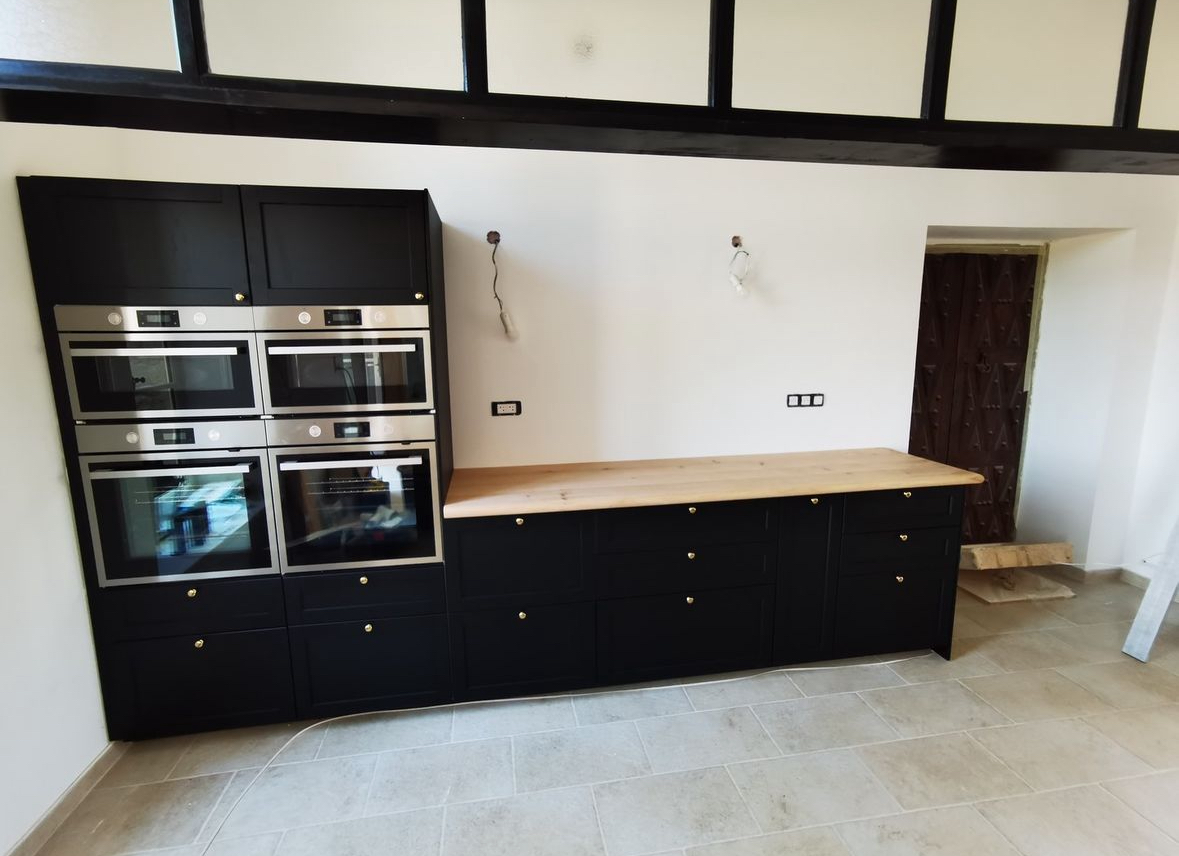 Intérieur de cuisine présentant des meubles noirs et des surfaces en bois, alliant sophistication et confort.